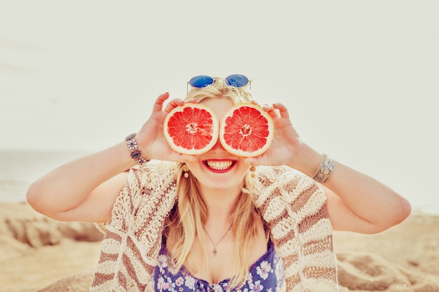 Photo joyful girl with half a grapefruit.