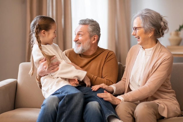 joyful grandparents enjoying quality time with their granddaughter indoors