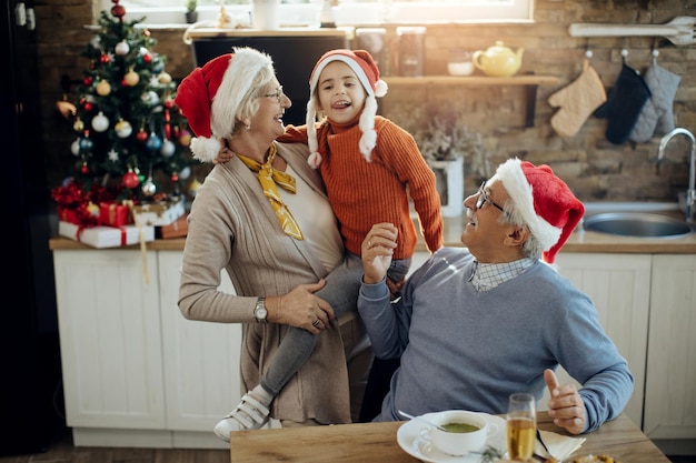 家でクリスマスの日に楽しんでいるうれしそうな祖父母とその孫娘