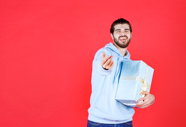 Joyful handsome man holding wrapped gift box and smiling