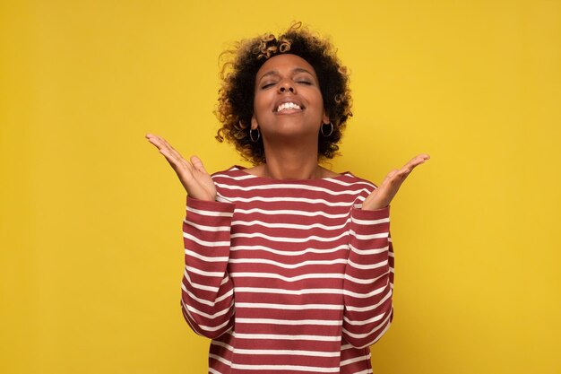 Joyful happy african american young woman joined hands thanking for good luck