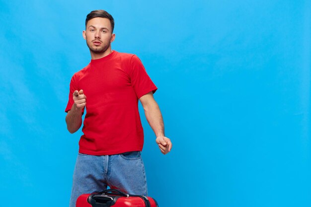 Joyful happy dancing tanned handsome man in red tshirt point\
finger at camera posing isolated on blue studio background copy\
space banner mockup trip journeys i choose you concept