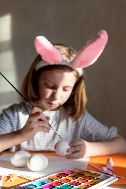 Joyful happy girl having fun and fooling around while decorating easter eggs for spring holidays sit