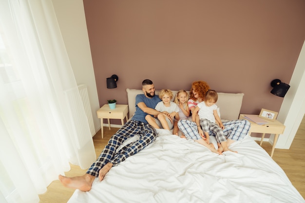 Joyful happy kids lying in the parents bed