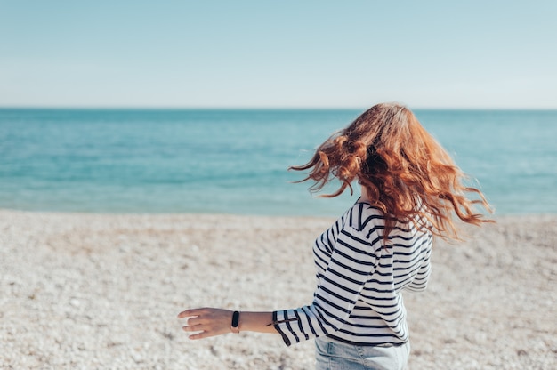 Joyful happy young redhead woman by sea