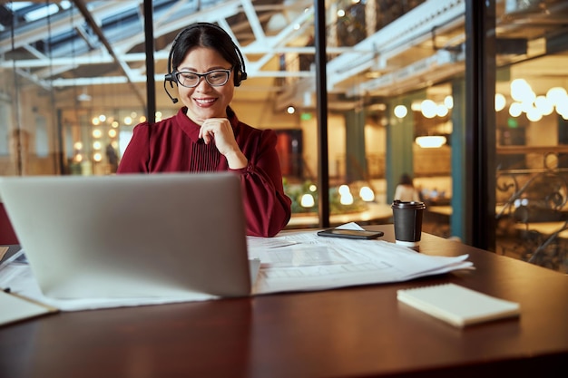 彼女のコンピューターを見ているうれしそうな国際的な女性