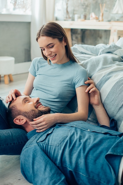 Joyful lady sitting and kindly smiling to a positive boyfriend lying on her laps