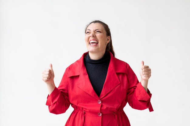 Joyful Latina woman on white background with big smile and raised thumbs