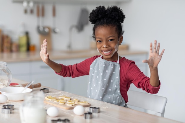 彼女の家族のためにクッキーを作るうれしそうな小さなアフリカ系アメリカ人の女の子