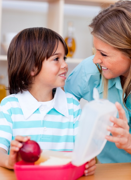 Joyful ragazzino e sua madre sta preparando il suo spuntino