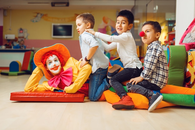 Joyful little boys sitting on funny clown in children's area.