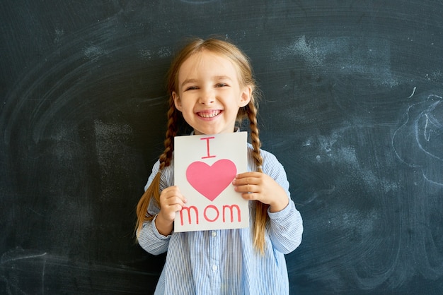 Joyful Little Girl Holding Greeting Card for Mom