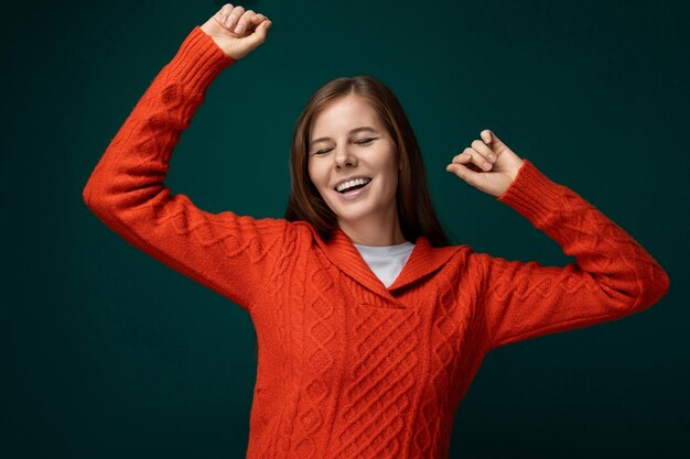 Joyful lucky woman wearing a red sweater on a dark green background