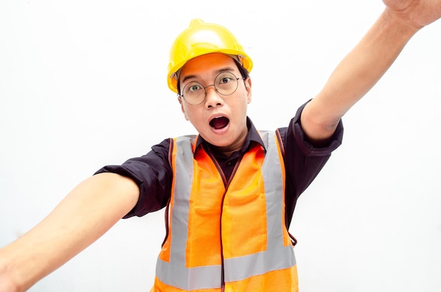 a joyful male construction worker or engineer taking selfie and holding camera with hands.