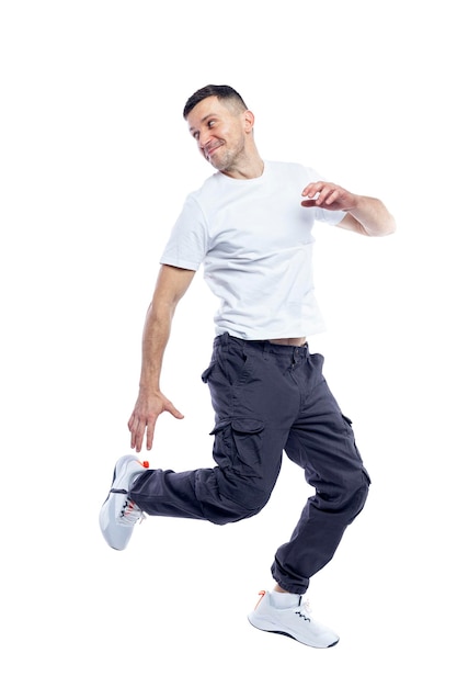 joyful man jumping brunette in a white tshirt and dark trousers sports activity and positive full height isolated on white background space for text