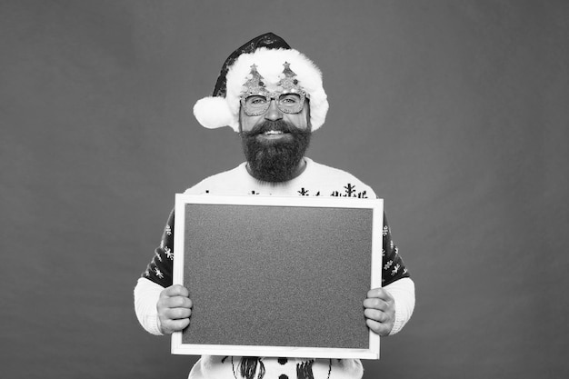 Joyful man show blackboard copy space Happy winter holidays Presentation or announcement Promoting winter goods and services Ski rental concept Winter price drop Bearded hipster Santa claus