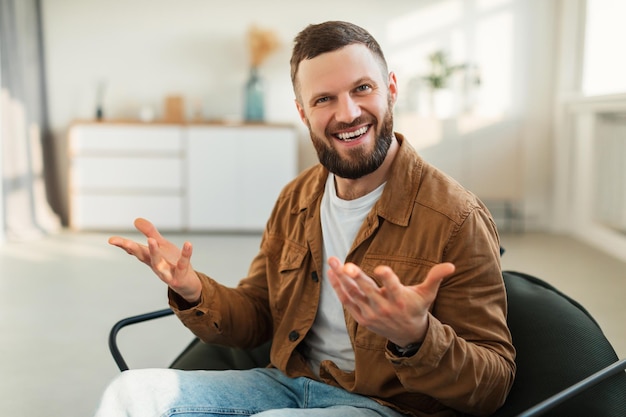 Joyful man smiling to camera sitting in chair at home