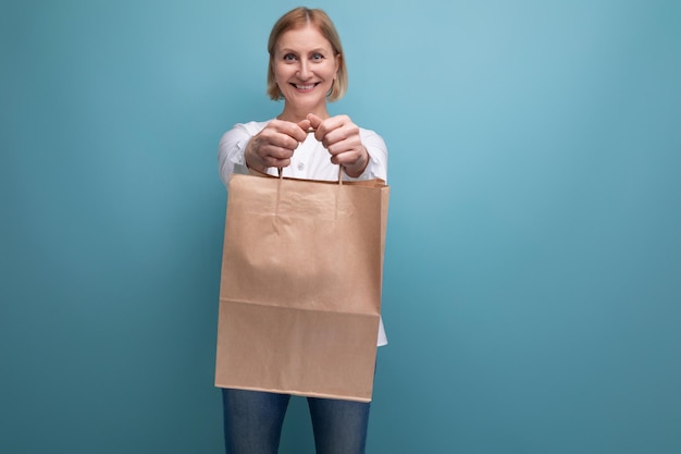 Joyful mature woman holding craft brown shopping bag