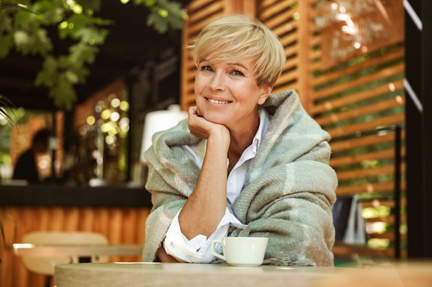 Photo joyful mature woman wrapped in blanket