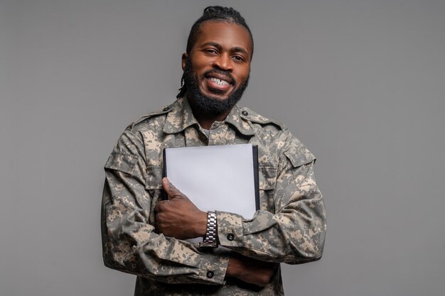 Joyful military man with documents looking ahead