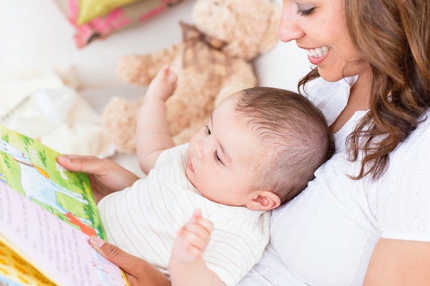 Joyful mother showing images in a book to her cute little son