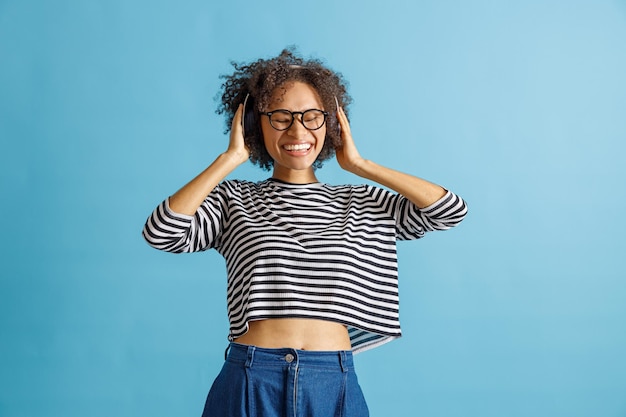 Joyful multiracial woman listening to music in studio