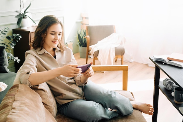 Joyful Multitasking Smiling young woman effortlessly types on her smartphone engages in a game an