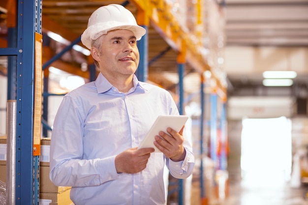 Joyful nice man working as a logistic manager in the warehouse