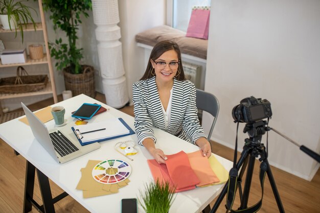 Joyful nice woman sitting at the table while being ready to record the video