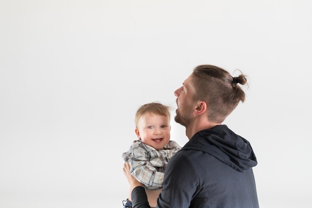 Joyful one year old kid is happy to spend time with his father copy space on white background