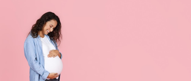 Joyful pregnant woman embracing her big tummy webbanner