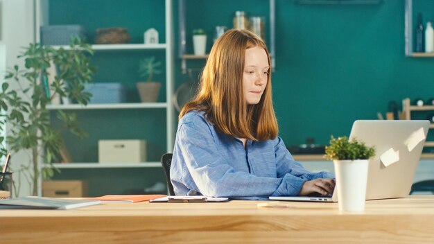 Joyful red haired teenage girl studying online comfortable home teaching online