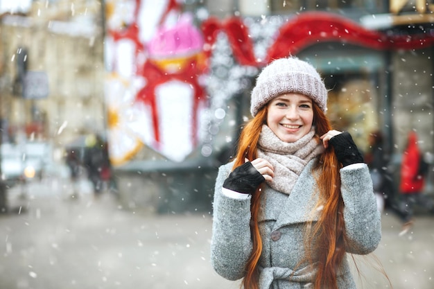 うれしそうな赤い髪の女性は、降雪時に街を歩いているコートを着ています。テキスト用のスペース