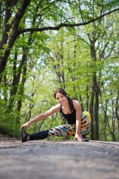 Joyful runner stretching her legs before a spring training in the nature