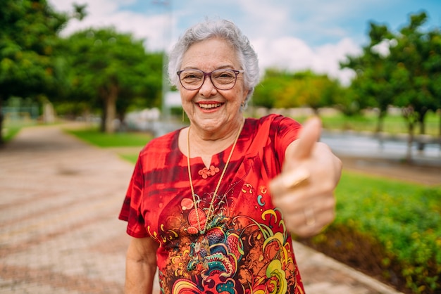 Photo joyful senior lady in glasses laughing up thumb. latin american woman. brazilian elderly woman.