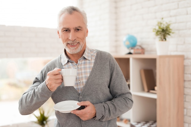 Joyful senior man drinking coffee at home.