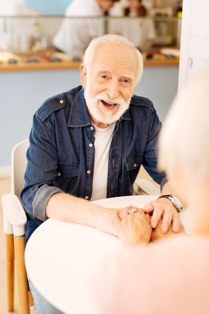 Foto uomo maggiore allegro che sorride e che prende le mani femminili