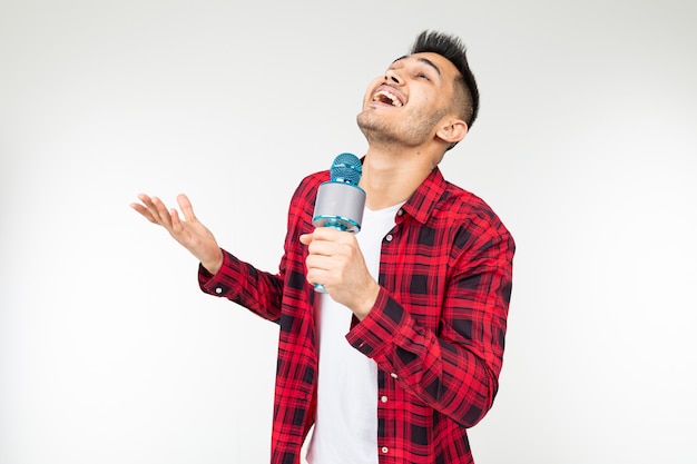 Joyful singer man in a shirt smiles and sings into a microphone on a white