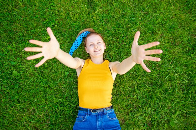 Радостная и улыбающаяся девушка лежит на траве