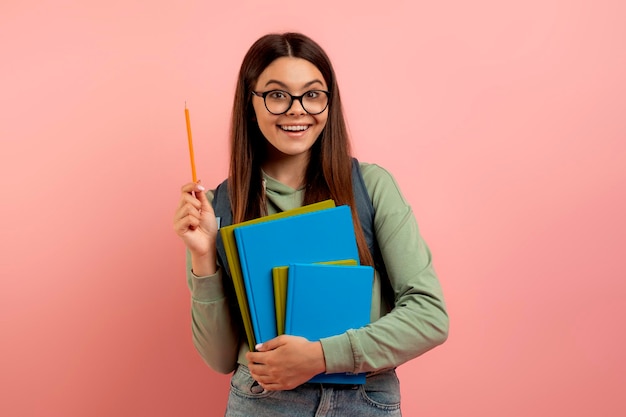 Joyful teen student with backpack and workbooks has a bright idea