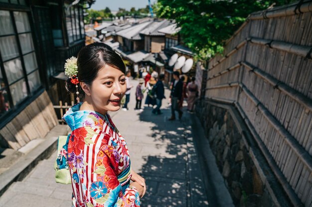 Photo joyful tourist with kimono and flower hairpin visiting sannen street in kyoto. asian young lady with colorful kimono robe standing on the famous stair in kyoto japan. travel in japan concept.