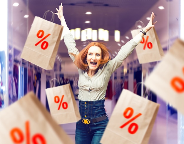 Photo joyful woman among sale paper bags in store