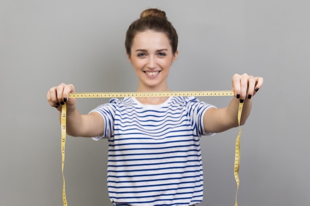 Joyful woman designer or seamstress showing measure tape dressmaker working measuring