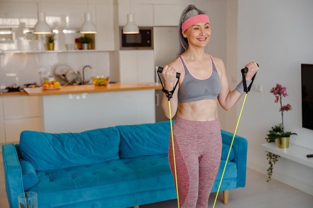 Joyful woman doing exercise with fitness rope at home