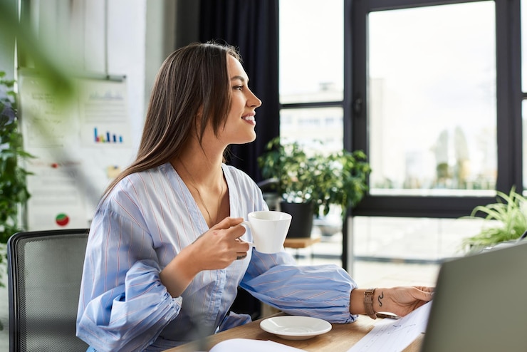 Photo joyful woman enjoying coffee while working in a bright modern office surrounded by greenery