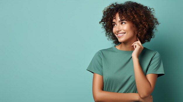 Joyful woman in green Tshirt and jeans laughs at the camera hands on hips against a green backdrop