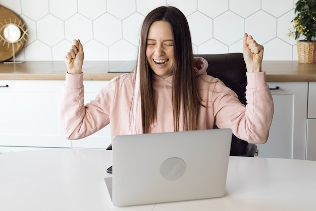 Photo joyful woman at laptop, remote quarantined work