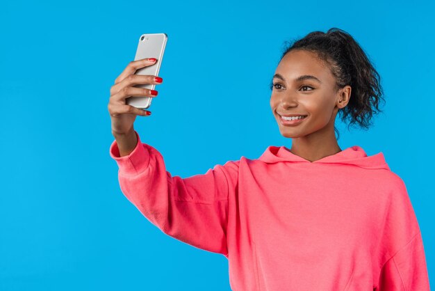 Donna gioiosa che fa selfie su smartphone su sfondo blu