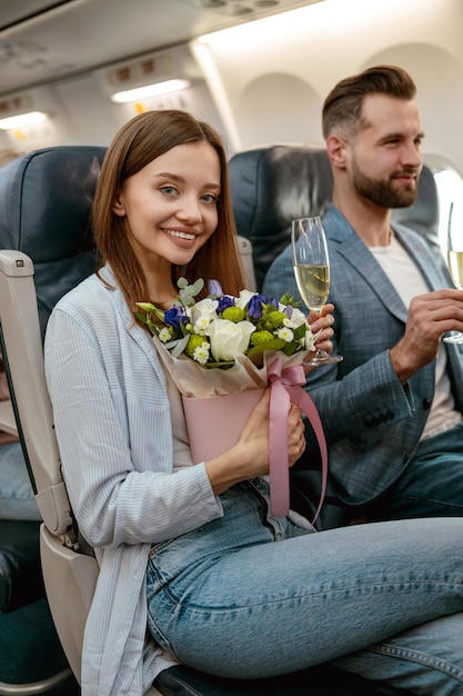 飛行機の中でシャンパンを飲むうれしそうな女性と男性