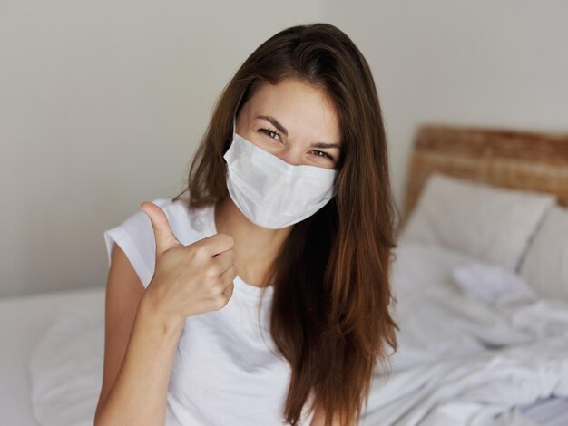 Joyful woman in medical mask showing thumb up